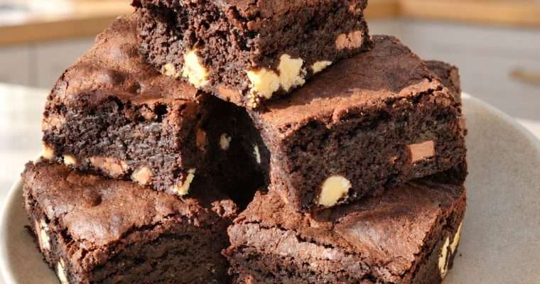 Fudgy triple chocolate brownies stacked on a plate