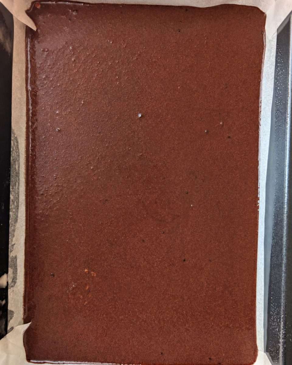 Raw chocolate cake batter in a slab tin ready to go in the oven